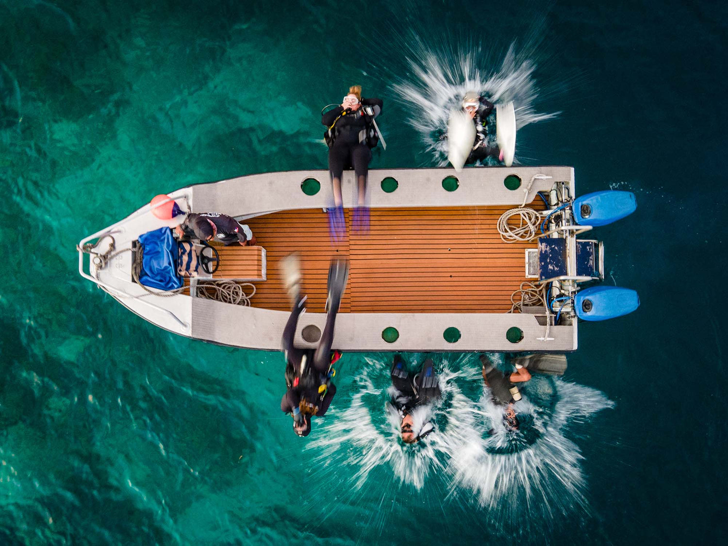 Grant Thomas' aerial image of divers back rolling into the water of Raja Ampat to scuba dive and take underwater photos